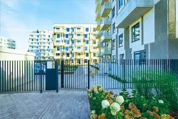 Modern apartment buildings with gated entrance and landscaped garden, representing properties purchased as-is by ROI National.