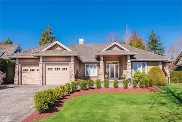 Pristine residential home with landscaped front yard, featuring a stone facade and double garage, representing ROI National's cash home buying services.