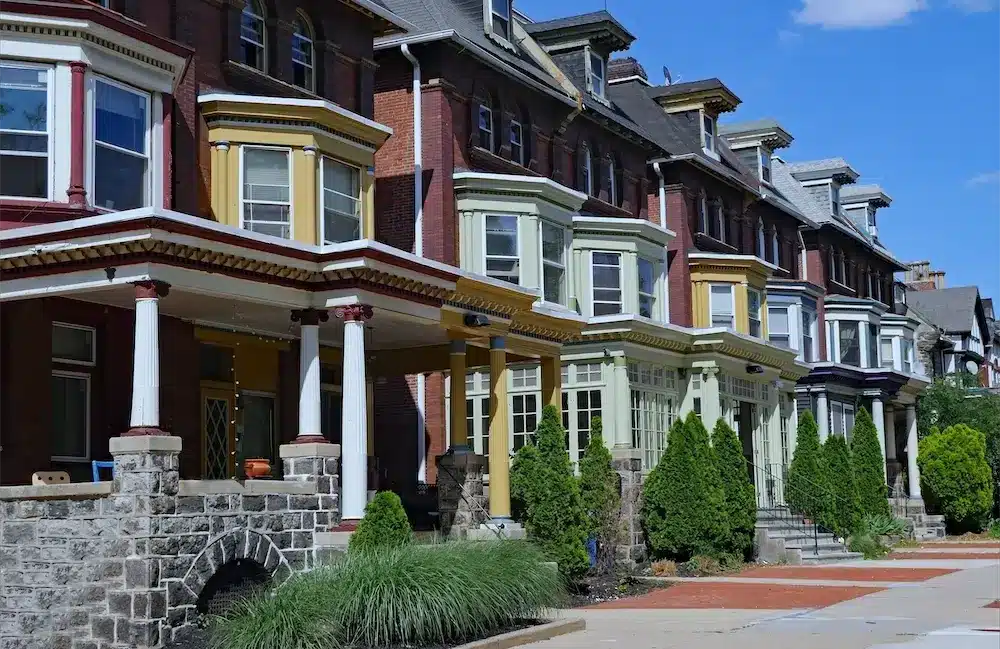 Row of colorful residential homes with porches and manicured lawns, representing properties available for quick cash offers by ROI National.
